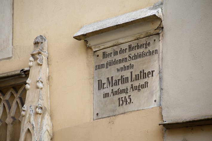 Hier ist eine Gedenktafel an einer Hauswand, die besagt: „Hier in der Herberge zum güldenen Schlosschen wohnte Dr. Martin Luther im Anfang August 1545.“