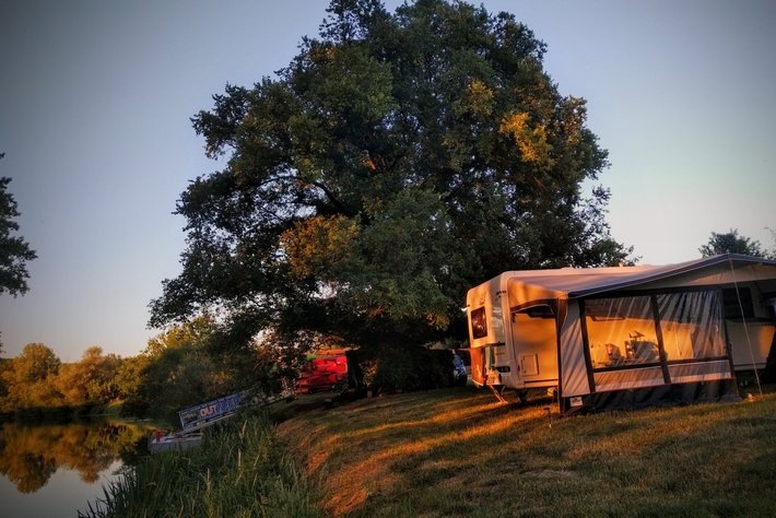 Wohnwagen auf einer grünen Wiese mit Zugang zum See