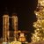 Ein beleuchteter Weihnachtsbaum mit vielen Lichtern ist vor einem im Dunkeln mähnlichen zu sehen, vermutlich eine Kathedrale oder Kirche.

Dominant sind die beleuchteten Türme mit typischen Spitzen.

Frohe Weihnachtsstimmung liegt in der Luft.?????